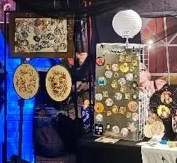 Framed wood burned rounds and a board of hand painted button magnets at the stall