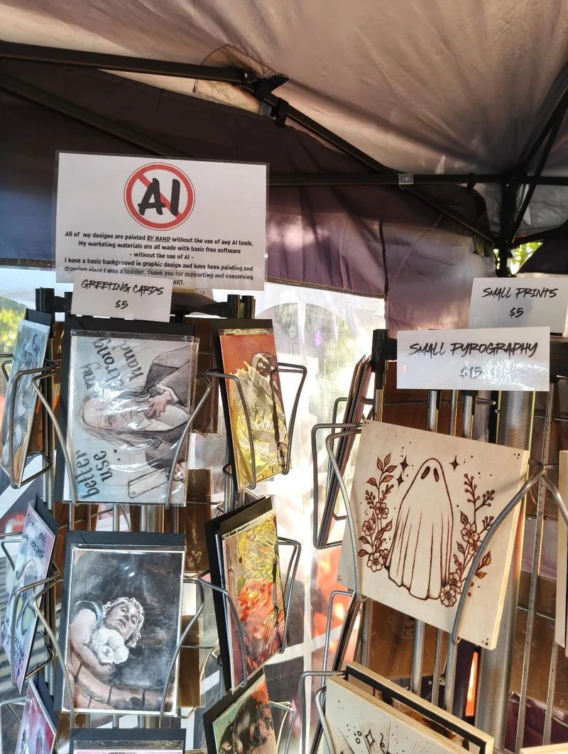 A close view of the booth’s card racks and small woodburned pieces beneath the canopy