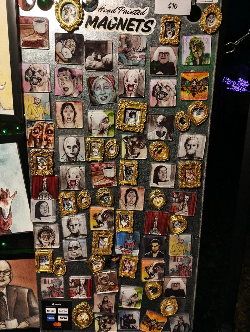 A black display board covered in small painted portrait magnets in different shapes and frames