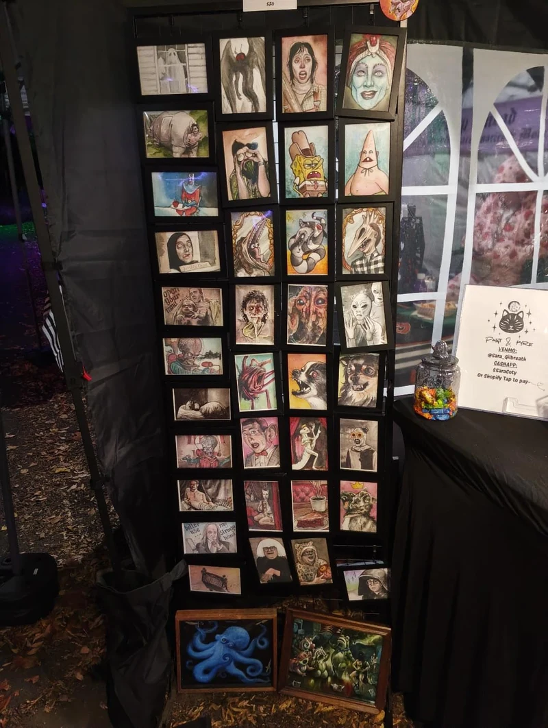 A tall black display of small colorful animal and character portraits inside Sara’s booth