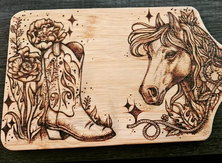 A bamboo serving board burned with a flowered cowboy boot on one side and a horse in profile on the other